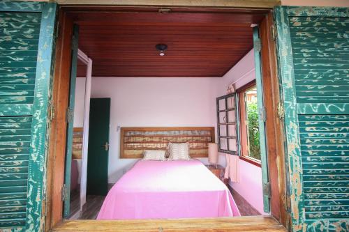 a bedroom with a bed in a room with a window at Pousada Vila Campeche in Florianópolis