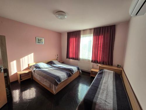 a bedroom with two beds and a window with red curtains at Comfort Apartment VT in Veliko Tŭrnovo
