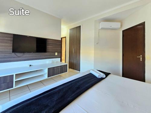 una camera d'albergo con un letto e una TV a schermo piatto di Linda casa 5 quartos prox a av cataratas e centro a Foz do Iguaçu