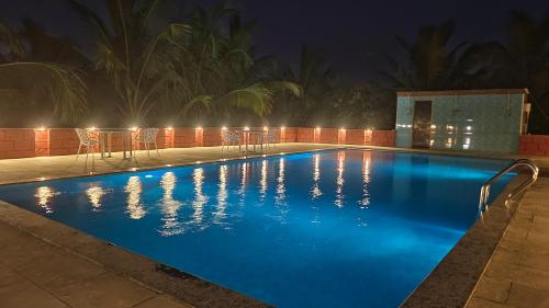 a swimming pool at night with chairs and lights at ParNam Hotel in Avas