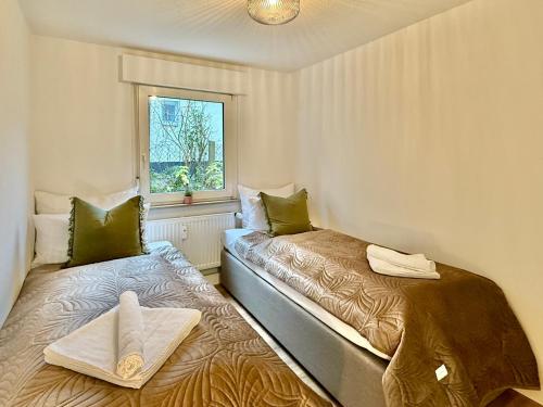 two beds in a small room with a window at CARICASA: Bielefeld Mitte in Bielefeld
