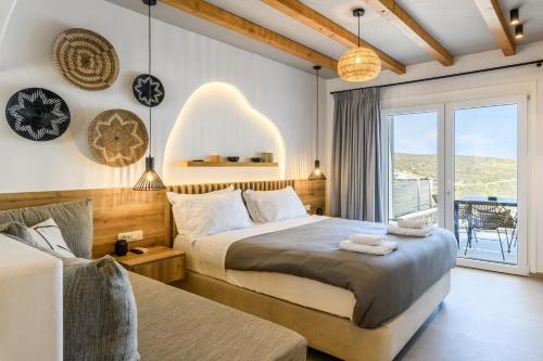 a bedroom with a large bed and a balcony at Mykonos Residence Villas & Suites Merchia beach in Merchia Beach