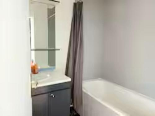 une salle de bain avec une baignoire, un lavabo et un rideau de douche dans l'établissement 3 Pièces, Paris Stade de France,parking, à Saint-Denis