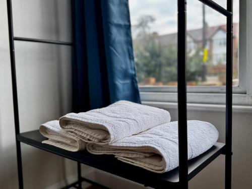 a shelf with towels on it next to a window at Maberic Housing West London Gem Your Central London Connection in London