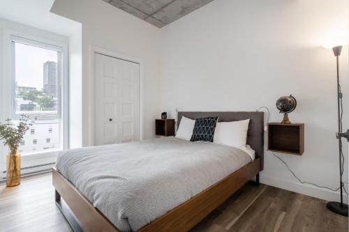 a white bedroom with a large bed and a window at Le Panorama - Parking gratuit - Toit terrasse in Quebec City