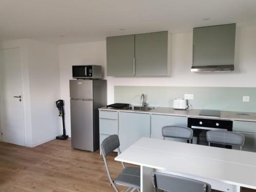 une cuisine avec des placards blancs et une table et des chaises blanches dans l'établissement Appartement neuf dans hameau proche porto vecchio, à Porto-Vecchio