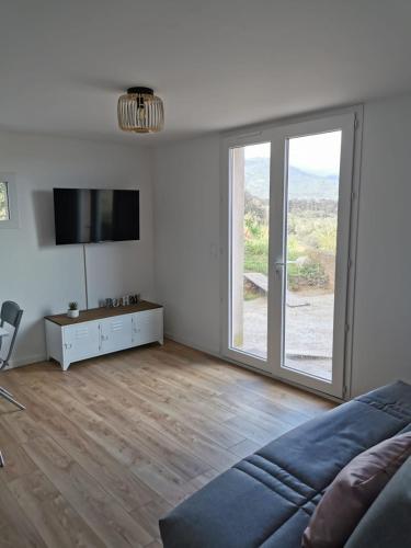 d'un salon avec une grande porte coulissante en verre. dans l'établissement Appartement neuf dans hameau proche porto vecchio, à Porto-Vecchio