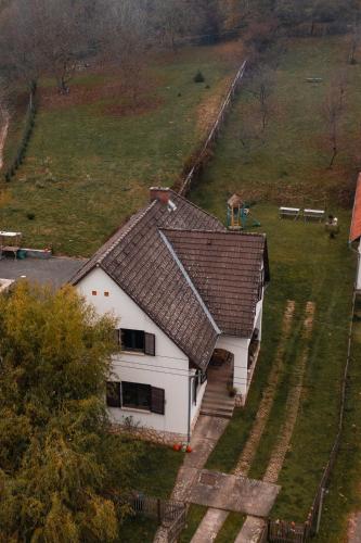 a white house with a brown roof in a field at Taurus Vendégház in Óbánya