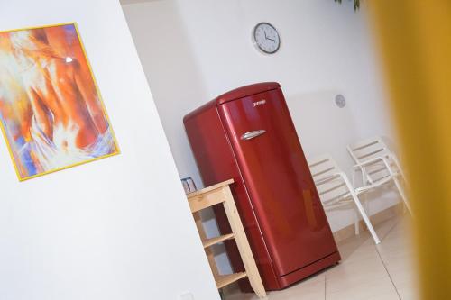 a red refrigerator in a room with a clock on the wall at Apart Franz Josef in Stumm