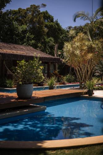a swimming pool in front of a house with trees at Villa Cozy in Arraial d'Ajuda