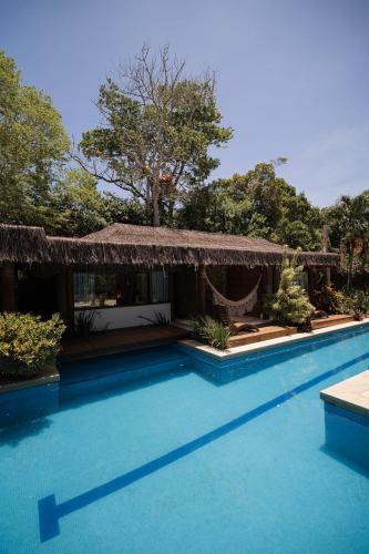 a swimming pool with a hammock and a resort at Villa Cozy in Arraial d'Ajuda