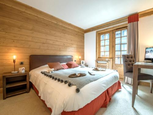 une chambre avec un grand lit avec un mur en bois dans l'établissement Duplex central à Courchevel avec cheminée, balcon, et WIFI - FR-1-575-147, à Courchevel