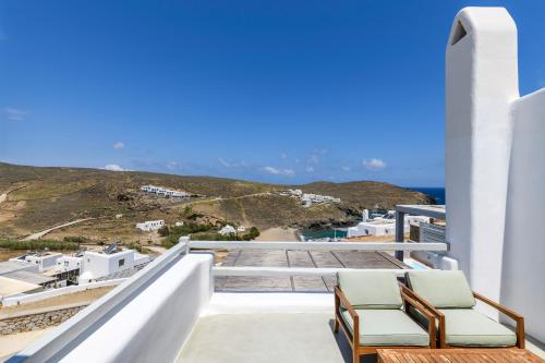 a balcony with two chairs and a view of the ocean at Mykonos Residence Villas & Suites Merchia beach in Merchia Beach