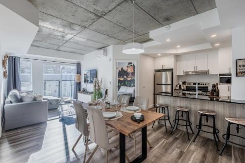 a kitchen and living room with a wooden table and chairs at L'Horizon Urbain, Centre Ville, Toit-Terrasse Gym in Quebec City