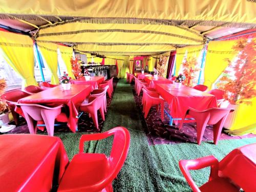 a restaurant with red tables and chairs in a tent at Ali jan hotel in Srinagar