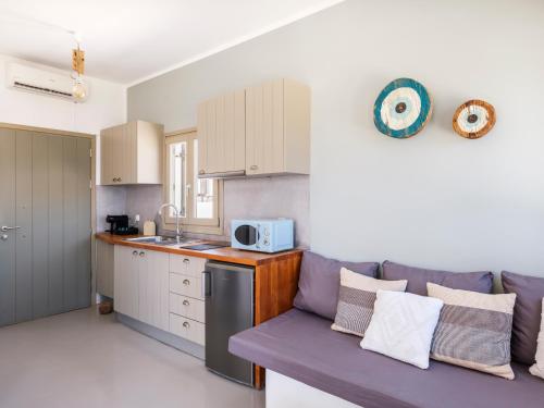 a living room with a purple couch and a kitchen at Mykonos Residence Villas & Suites Merchia beach in Merchia Beach