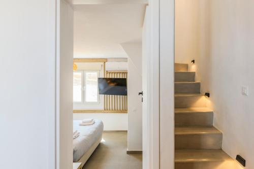 a bedroom with a bed and a staircase in a room at Mykonos Residence Villas & Suites Merchia beach in Merchia Beach
