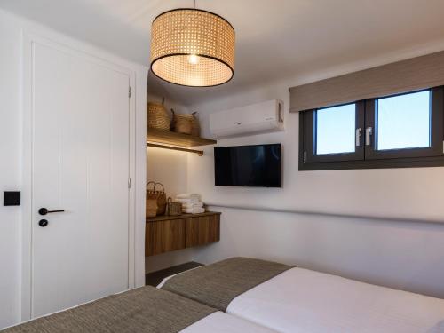 a bedroom with a bed and a flat screen tv at Mykonos Residence Villas & Suites Merchia beach in Merchia Beach