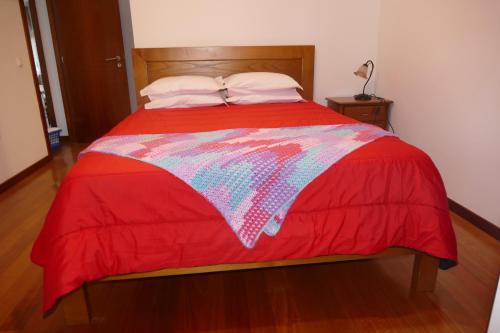a bed with a red blanket on top of it at Casa nos Penedos in Arcos de Valdevez