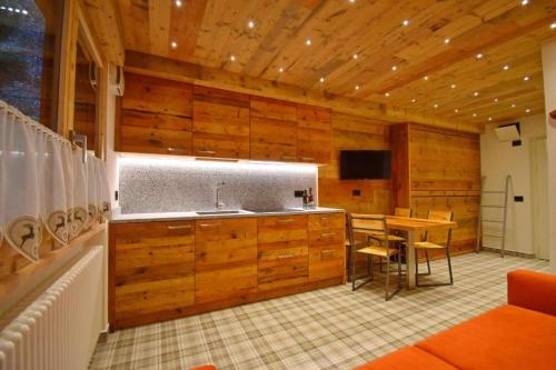 a kitchen with wooden cabinets and a table in a room at Hotel Betulla in Madonna di Campiglio