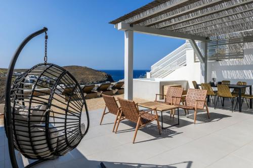 a patio with a table and chairs and a swing at Mykonos Residence Villas & Suites Merchia beach in Merchia Beach