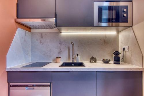 une cuisine avec un évier et un micro-ondes dans l'établissement L'Oasis - Bel appart climatisé quartier point du jour Lyon 5, à Lyon