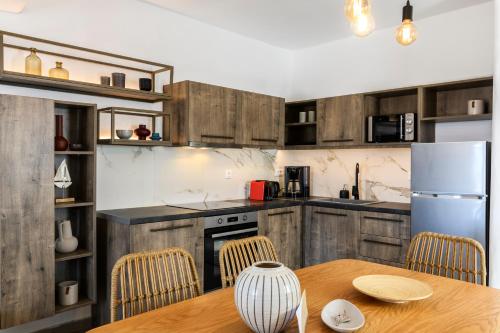 a kitchen with wooden cabinets and a table and a refrigerator at Mykonos Residence Villas & Suites Merchia beach in Merchia Beach