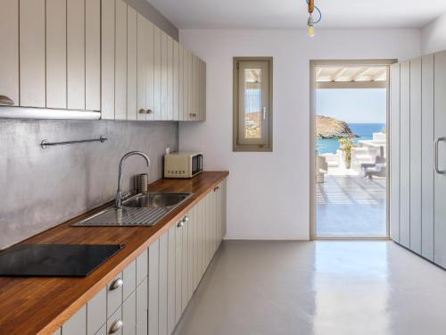 a kitchen with a sink and a view of the ocean at Mykonos Residence Villas & Suites Merchia beach in Merchia Beach
