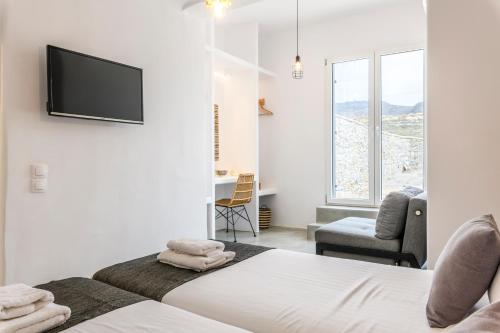 a bedroom with a bed and a tv on a wall at Mykonos Residence Villas & Suites Merchia beach in Merchia Beach