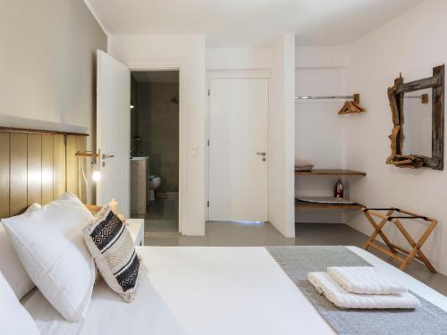 a bedroom with a white bed and a bathroom at Mykonos Residence Villas & Suites Merchia beach in Merchia Beach