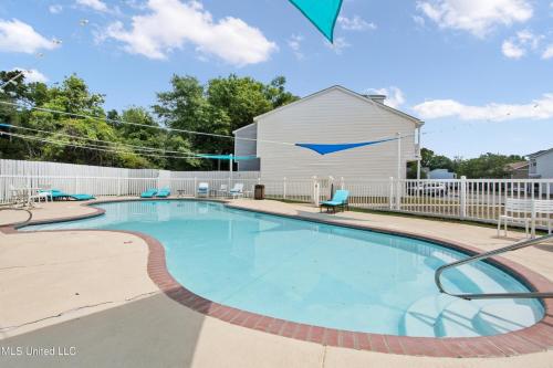 a swimming pool with a white fence and a building at Sunset Beach Hideaway in Gulfport