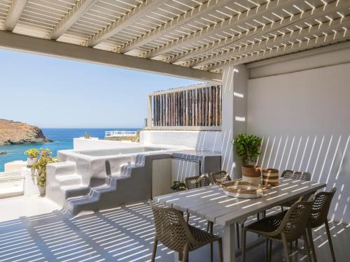 a patio with a table and chairs and the ocean at Mykonos Residence Villas & Suites Merchia beach in Merchia Beach