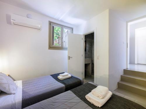 a small bedroom with two beds and a bathroom at Mykonos Residence Villas & Suites Merchia beach in Merchia Beach