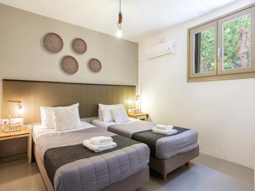 a bedroom with two beds and two windows at Mykonos Residence Villas & Suites Merchia beach in Merchia Beach