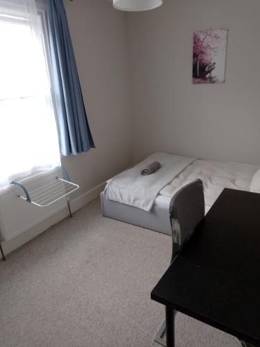 a bedroom with a bed and a table and a window at Double or twin room in town centre in East Grinstead