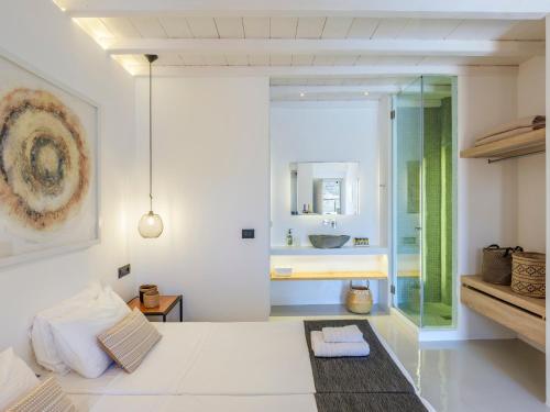 a bedroom with a white bed and a bathroom at Mykonos Residence Villas & Suites Merchia beach in Merchia Beach