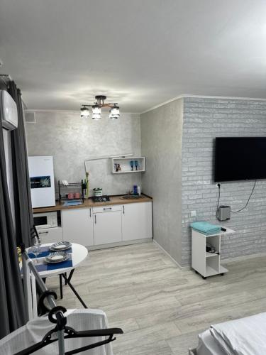 Una sala de estar con una mesa y un televisor. en Центр Чехова 100, en Kostanái