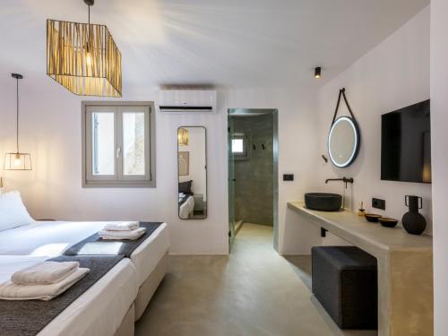 a bedroom with a bed and a sink and a mirror at Mykonos Residence Villas & Suites Merchia beach in Merchia Beach