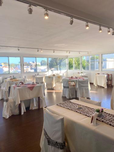 una sala da pranzo con tavoli bianchi e sedie bianche di Hotel Centro a Piriápolis