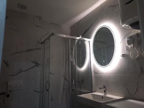 a bathroom with a shower and a sink and a mirror at MN apartman in Banja Luka