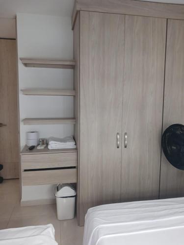 a bedroom with a bed and a wooden cabinet at Jardin imperial, habitaciones para tu disfrute y descanso en apto familiar in Cartagena de Indias
