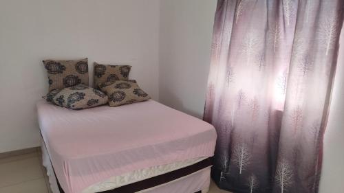 Cama pequeña en habitación con cortina rosa en Discovery Guest House, en Roodepoort