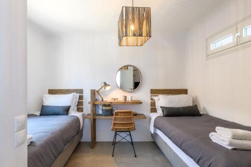 two beds in a room with a mirror and a stool at Mykonos Residence Villas & Suites Merchia beach in Merchia Beach