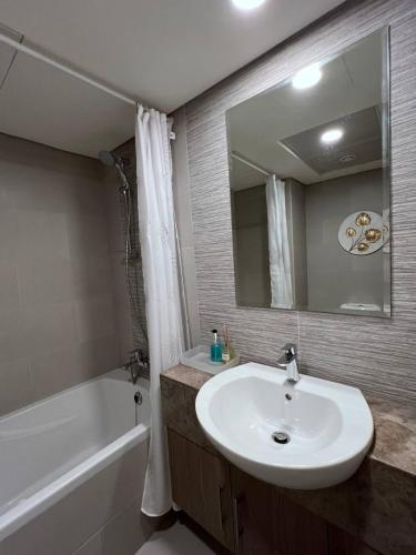 a bathroom with a sink and a tub and a mirror at Cozy Studio - Your Comfort First! in Abu Dhabi