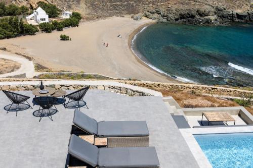 a patio with a table and chairs next to a beach at Mykonos Residence Villas & Suites Merchia beach in Merchia Beach