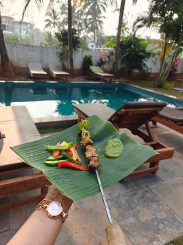 a person holding a green plate with vegetables on it at SOLS Backyard in Arambol