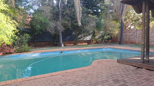 a swimming pool in a yard with a brick wall at Ithiliens Grace Guesthouse in Pretoria