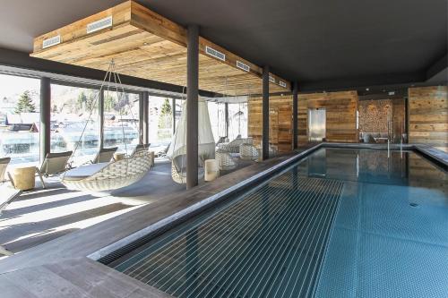 a swimming pool with a hammock and chairs in a house at Hotel Edelweiss in Saalbach Hinterglemm