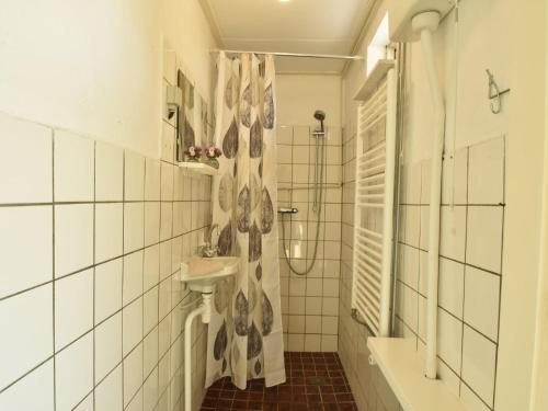 a white tiled bathroom with a sink and a shower at Holiday home in surroundings nearby the coast in Callantsoog