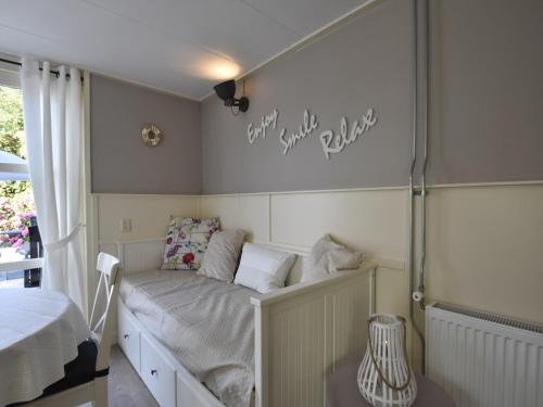 a small bedroom with a bed with white sheets at Holiday home in surroundings nearby the coast in Callantsoog